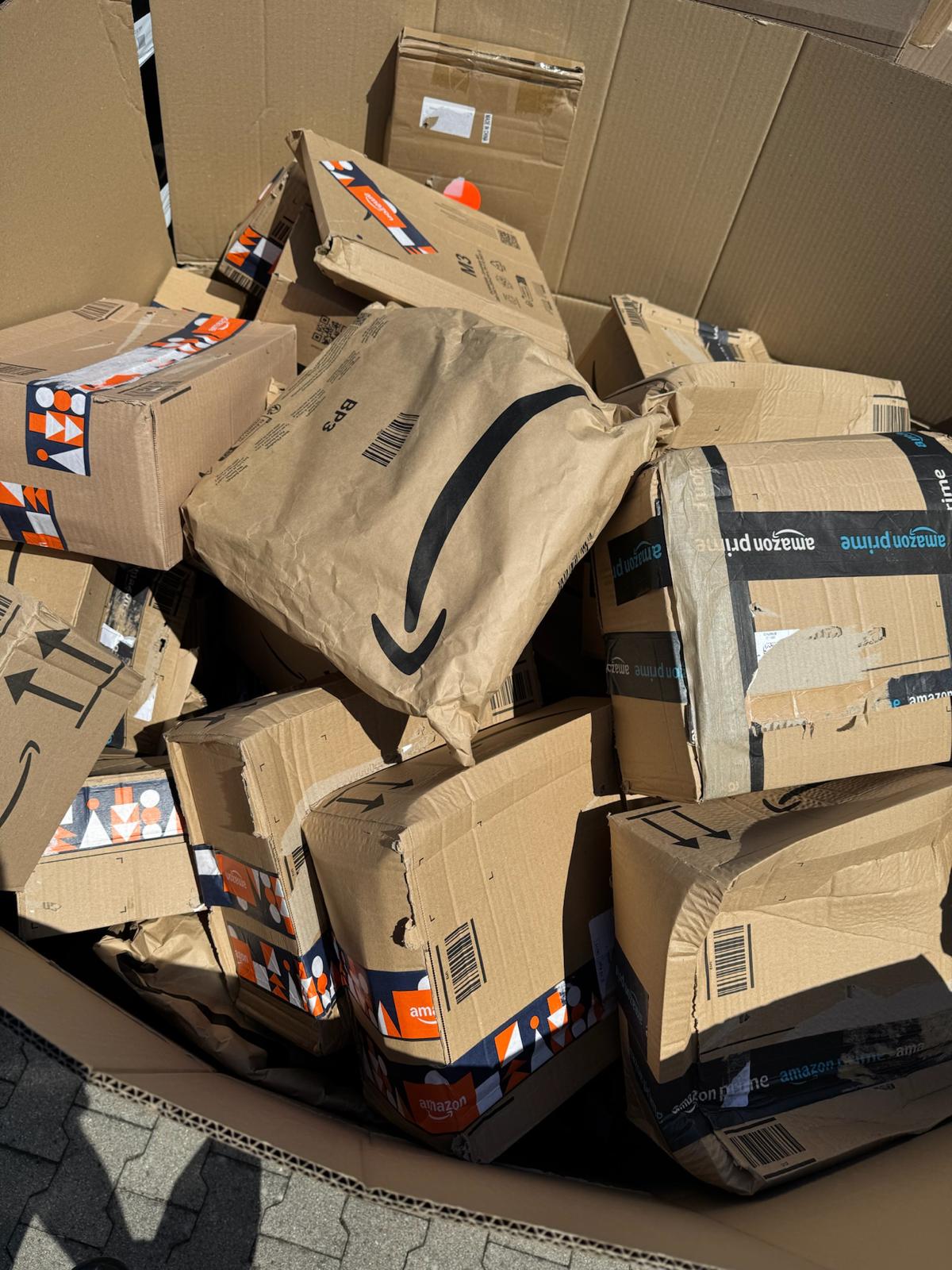 Amazon-Kartons und eine Versandtasche mit Amazon-Logo als Beispiel für die Pakete am Hall-of-Secrets-Stand.